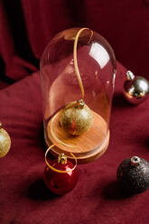 High angle of shiny Christmas bauble in glass dome placed on table at home for holiday - ADSF17636