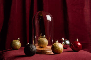 High angle of collection of sparkling Christmas balls arranged on red soft bed at home - ADSF17637