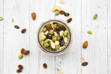 Jar of raisins, peanuts, cashew nuts, almonds, soybeans, sunflower seeds and pumpkin seeds on wooden background - LVF09070