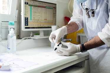 Male dentist preparing denture while standing at clinic - JCMF01645