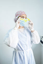 Kieferorthopäde in Arbeitsschutzkleidung mit Gesichtsschutz, während er in der Klinik während Covid-19 steht - JCMF01664