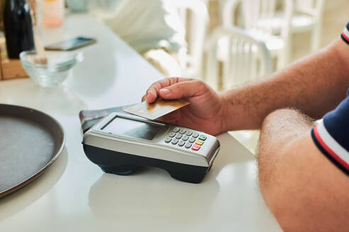 Von oben von Ernte unerkennbar männlichen Kunden zahlen für die Bestellung per Kreditkarte mit Zahlungsterminal in modernen Café - ADSF17708