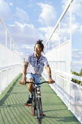 Mann hört Musik beim Fahrradfahren auf einer Brücke - IFRF00091