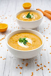 Two bowls of vegetarian lentil soup with carrots, orange juice, creme fraiche and parsley - LVF09073