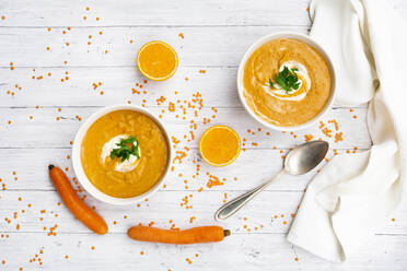 Two bowls of vegetarian lentil soup with carrots, orange juice, creme fraiche and parsley - LVF09075