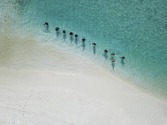 Women in traditional muslim clothes at tropical beach, aerial view - KNTF05824