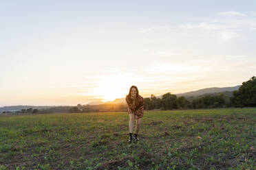 Young woman enjoying sunset at countryside against sky - AFVF07619