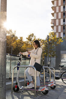 Unternehmerin beim kontaktlosen Bezahlen an einer Fahrradparkstation in der Stadt - AFVF07632