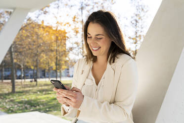 Businesswoman text messaging on smart phone in park - AFVF07659