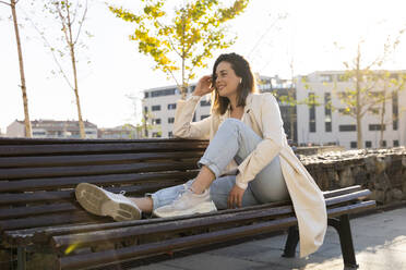 Glückliche Frau auf einer Bank sitzend an einem sonnigen Tag - AFVF07672