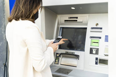 Unternehmerin beim Geldabheben am Geldautomaten während der COVID-19 - AFVF07698