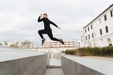 Mann springt auf Wand gegen klaren Himmel - FMOF01224