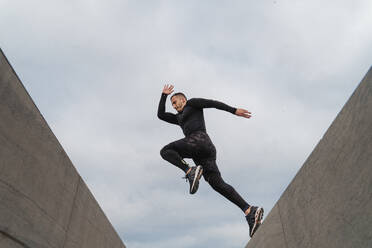 Sportler springt auf Wand gegen Himmel - FMOF01225