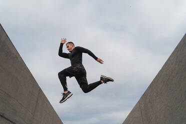 Athlete jumping on wall against sky - FMOF01226