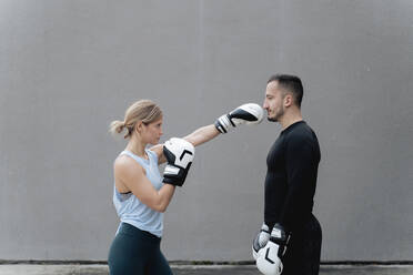 Sportswoman practicing boxing while standing against wall - FMOF01242