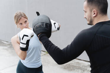 Sportsman and woman practicing boxing while standing against wall - FMOF01256