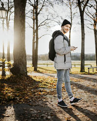 Mann hält Smartphone während eines Herbstspaziergangs im Park - MKF00022
