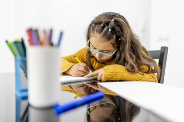 Mädchen zeichnet in Buch auf Tisch zu Hause - OCMF01851