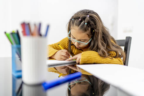 Mädchen zeichnet in Buch auf Tisch zu Hause - OCMF01851