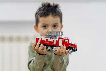 Niedlicher Junge hält Feuerwehrauto-Spielzeug zu Hause - OCMF01854