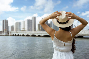 Young woman wearing hat while standing at bay - MAUF03596