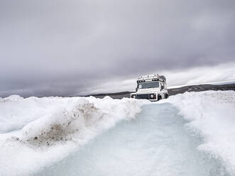 Geländewagen auf Schneelandschaft gegen bewölkten Himmel, Langjokull, Island - LAF02617