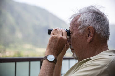 Älterer Mann betrachtet die Aussicht durch ein Fernglas - MAMF01429
