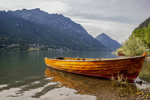 Boat on lakeshore against mountain during sunny day - MAMF01432