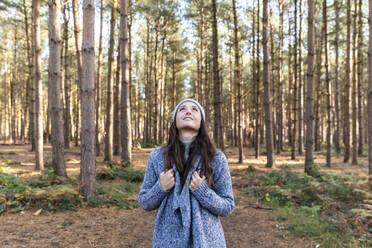 Mid adult woman looking up while exploring in Cannock Chase forest - WPEF03651