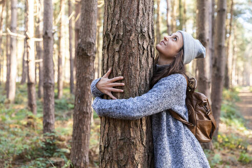 Wanderin umarmt Baumstamm bei der Erkundung eines Waldgebiets in Cannock Chase - WPEF03654