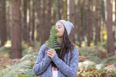 Eine Wanderin hält ein Farnblatt in der Hand, während sie im Waldgebiet Cannock Chase steht - WPEF03675