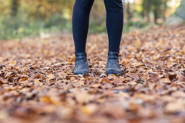 Frau in Stiefeln steht auf einem Herbstblatt im Waldgebiet Cannock Chase - WPEF03677