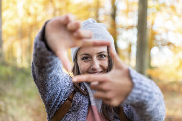 Frau formt Rahmen mit Finger, während sie im Wald von Cannock Chase steht - WPEF03693