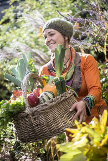 Frau, die im Garten stehend Obst und Gemüse sammelt - HHF05598
