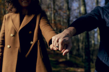 Paar hält sich an den Händen, während es im Wald steht - FMOF01302