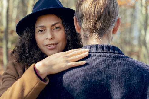 Frau mit Hut umarmt Mann, während sie im Wald steht - FMOF01306