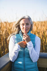 Grauhaarige Frau genießt einen Naturspaziergang im goldenen Sumpf - CAVF90617