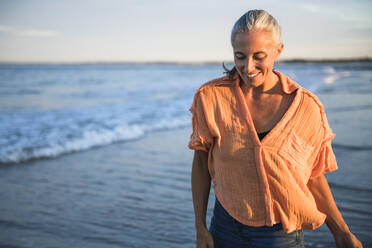 Gray Haired Woman enjoying the beach at sunset - CAVF90629