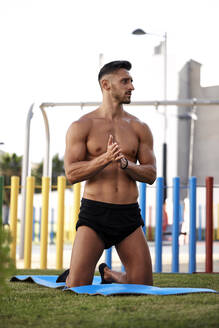 Ein junger, kräftiger Mann macht Gymnastik auf einer Fitnessmatte - CAVF90684