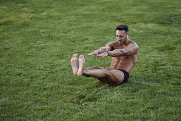 Ein Mann ohne Hemd macht harte Gymnastik auf dem Rasen - CAVF90694