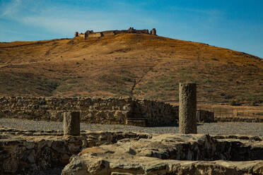 View of stone columns and hill with castle in the background - CAVF90720