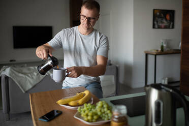 Erwachsener Mann gießt morgens Tee ein - CAVF90742