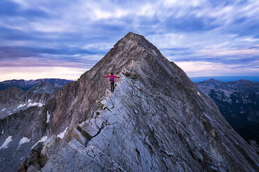 Rückansicht einer Wanderin, die mit ausgestreckten Armen auf einem Bergkamm steht - CAVF90778