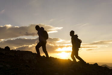 Silhouette female hikers on mountain against sky during sunrise - CAVF90779