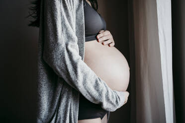 Pregnant woman in bra and panties holding stomach stock photo