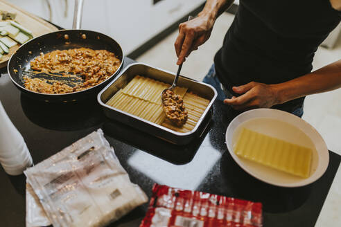 Frau macht Lasagne, während sie in der Küche zu Hause steht - DMGF00309