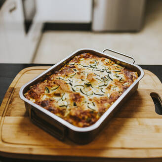 Hausgemachte gekochte Lasagne mit Zucchini in der Schale auf dem Schneidebrett zu Hause - DMGF00313