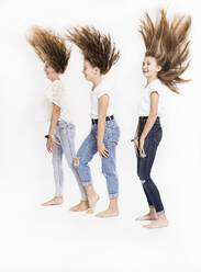 Playful sisters tossing hair against white background - SDAHF00988