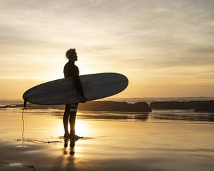 Silhouette Mann mit Surfbrett am Strand bei Sonnenuntergang - KBF00645