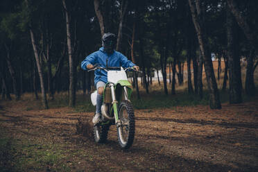 Männlicher Jugendlicher fährt Motorrad auf unbefestigtem Weg im Wald - ACPF00900